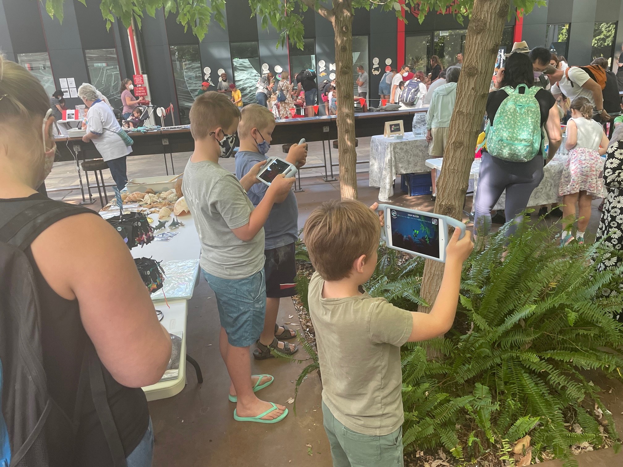 Several children at the Marine Discovery Centre, playing with iPads with a Discovery Dive game