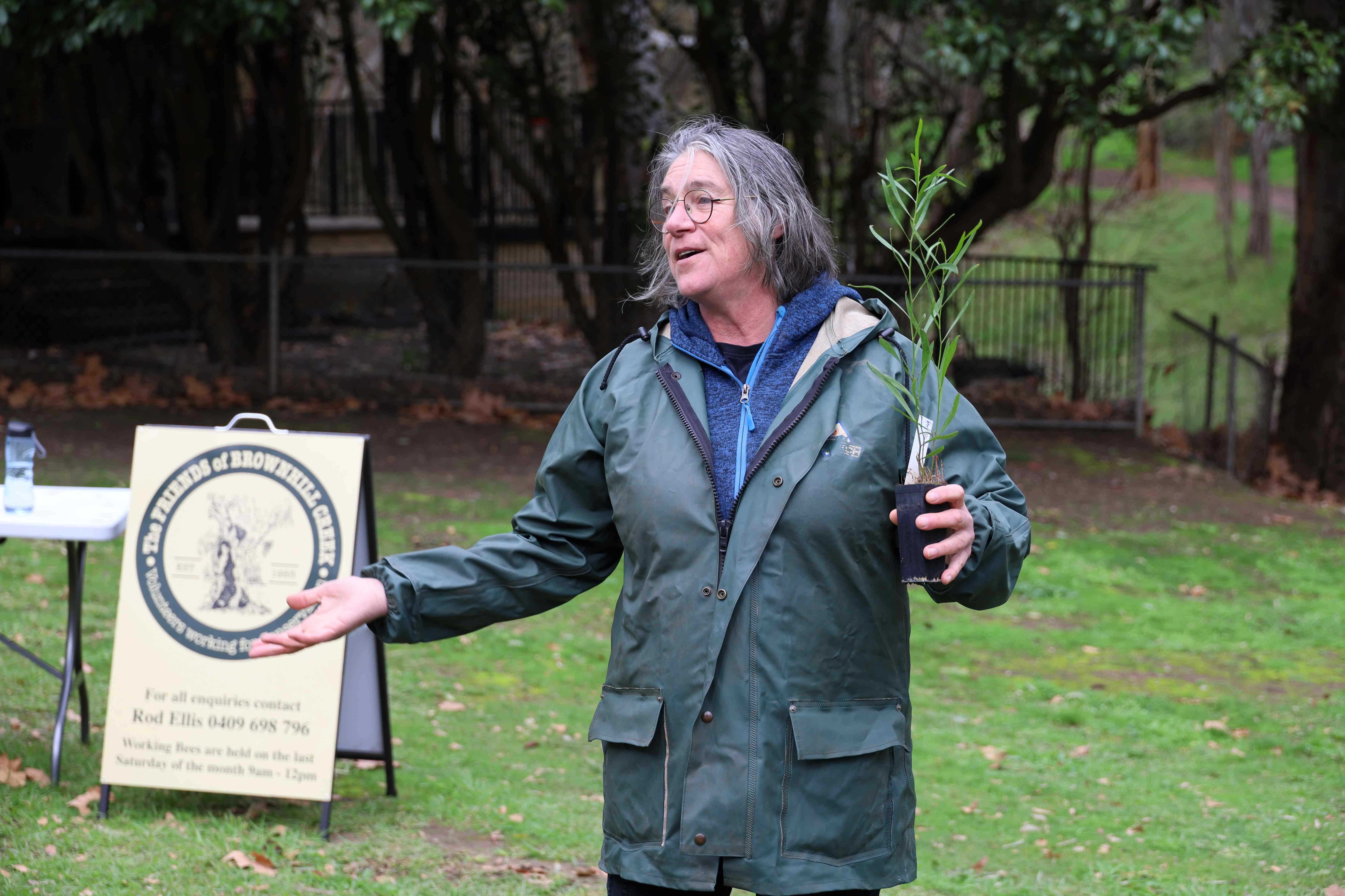 Katja stands looking off camera, holding a seedling