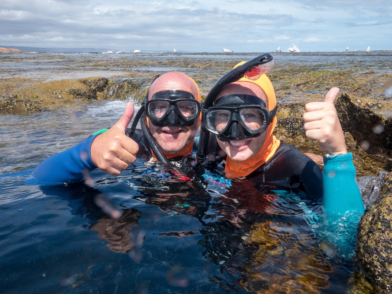 Two people snorkelling, giving a thumbs up to the camera